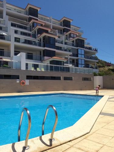 a swimming pool in front of a large building at Apartamento Doreen in Caniço
