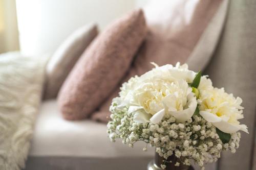 a vase filled with white flowers on a couch at Casa PERLA in Dunajská Streda