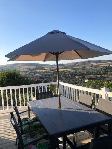a blue table with an umbrella on a deck at 225 Buttercup Swanage Bay View - Vacation Home in Swanage