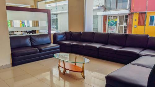 a living room with a leather couch and a glass table at Hotel María Eugenia Tuxtla Gutiérrez in Tuxtla Gutiérrez