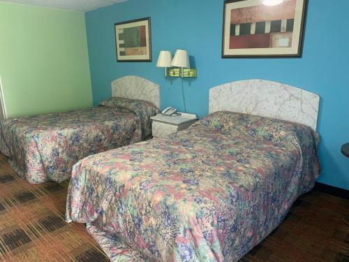 2 camas en una habitación de hotel con paredes azules en Seminole Inn, en Donalsonville
