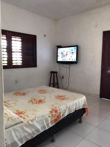 a bedroom with a bed and a flat screen tv at Praia da Baleia Itapipoca CE in Franco