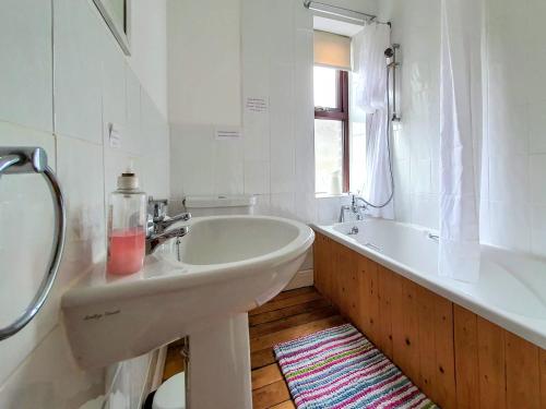 a white bathroom with a sink and a tub at Bronte Railway Cottage at Haworth in Haworth