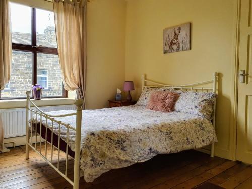 a bedroom with a bed and a window at Bronte Railway Cottage at Haworth in Haworth