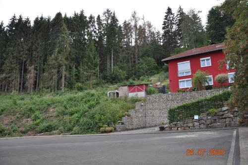 a red house on a hill next to a road at Ferienwohnung Idarblick in Idar-Oberstein