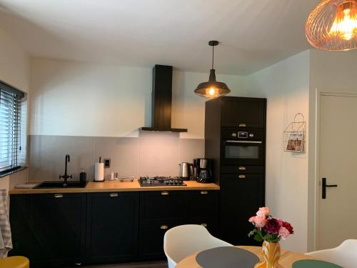 a kitchen with black cabinets and a table at Gouden Hert: relaxen in comfort! #otterlo #hogeveluwe in Otterlo