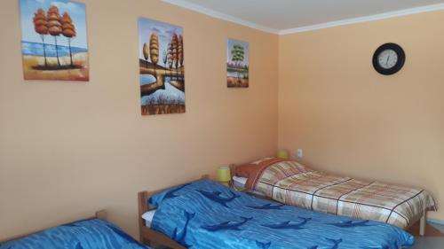a bedroom with two beds and a clock on the wall at Andi Apartman in Pačir