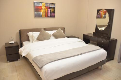 a bedroom with a large bed and a mirror at Montecito Apartments in Accra