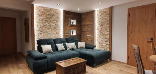 a living room with a blue couch and a brick wall at HIESERHOF - Superior Alpine Apartments in Heiligenblut