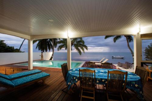 a deck with a table and chairs and a swimming pool at Villa Tepoe Pool and Beach in Moorea