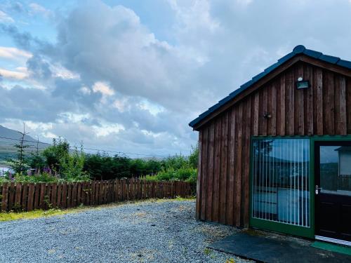 a wooden shed with a glass door on a gravel road at Hazelmount Self-Catering Cabin in Portree