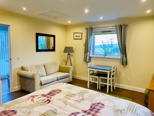 a bedroom with a bed and a couch and a table at Hazelmount Self-Catering Cabin in Portree