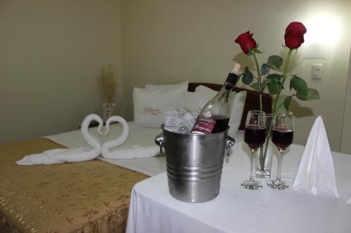 a table with two glasses of wine and a bucket of flowers at Alejandra Hotel in Chiclayo