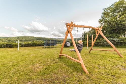 a man sitting on a swing in a field at Chata Krušnohorka in Kovářská