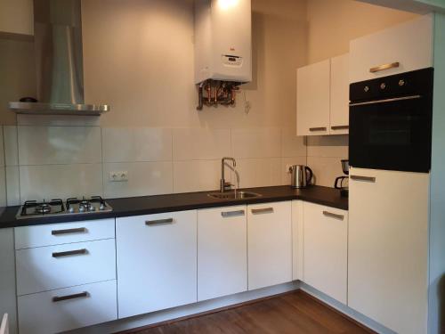 uma cozinha branca com armários brancos e electrodomésticos pretos em De Patrijs em Oudemirdum
