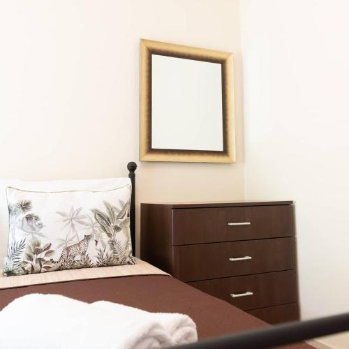 a bedroom with a bed with a dresser and a mirror at Evdokia's Apartments and Rooms in Neos Marmaras