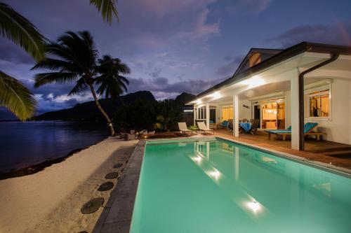 a house with a swimming pool next to the ocean at Villa Tepoe Pool and Beach in Moorea