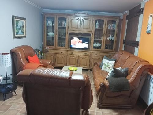 een woonkamer met 2 leren stoelen en een televisie bij CASA O QUINTEIRO in Vimianzo