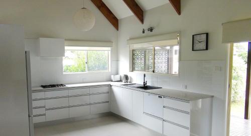 a white kitchen with white cabinets and a window at Pitcairn House in Burnt Pine