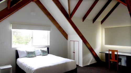 a attic bedroom with a bed and a window at Pitcairn House in Burnt Pine