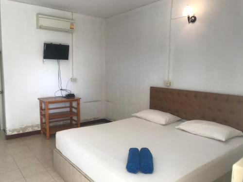 a bedroom with a bed with two blue shoes on it at สวนไผ่รีสอร์ท in Ban Na
