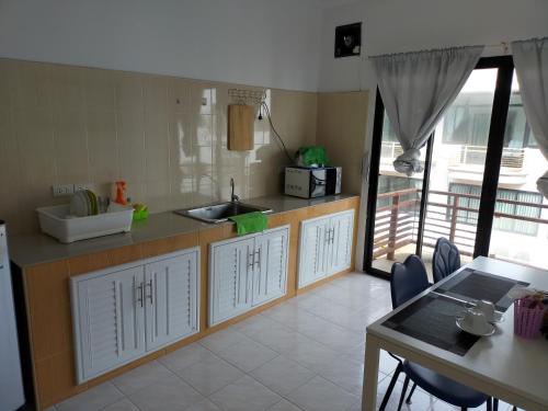Amy's beach apartments في رايونغ: مطبخ مع حوض وطاولة مع كراسي