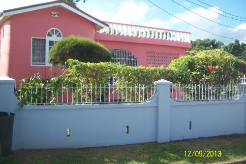 a white fence in front of a pink house at Tina's Guest House in Ocho Rios