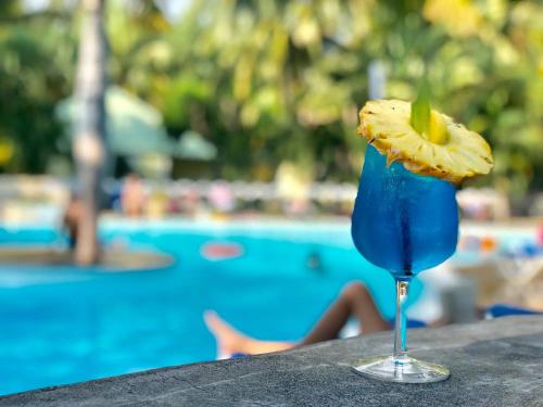 a blue drink sitting on a table next to a pool at Hotel Exsel Floralys in Étang-Salé les Bains