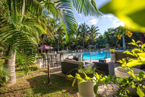 uma vista para uma piscina com palmeiras em Hotel Exsel Floralys em Étang-Salé les Bains