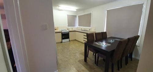 a kitchen with a table, chairs and a refrigerator at Pinjarra Caravan Park and Cabins in Pinjarra