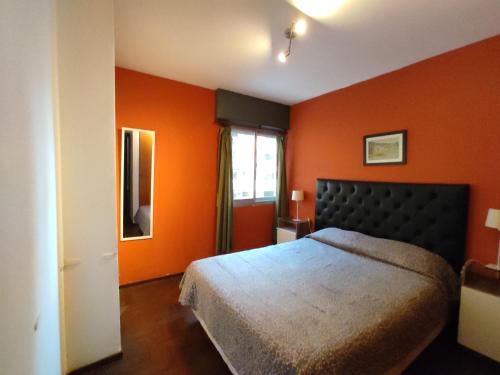 1 dormitorio con paredes de color naranja, 1 cama y ventana en Apartamento Pueyrredón en Córdoba