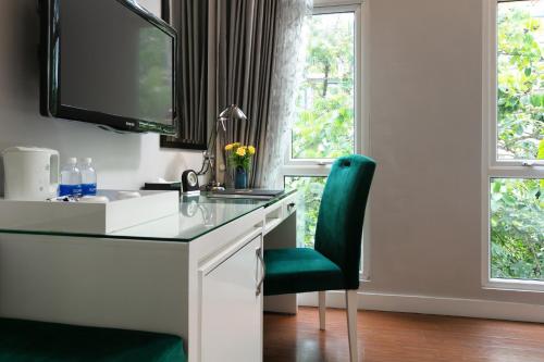 a desk with a green chair in a room with windows at Minerva Church Hotel in Hanoi