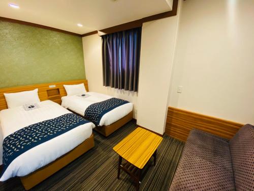um quarto de hotel com duas camas e uma cadeira em Ueno Touganeya Hotel em Tóquio