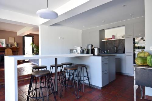 une cuisine avec un comptoir blanc et des tabourets de bar dans l'établissement Villa 7 chambres avec grande piscine à 600 m de la plage, à Royan