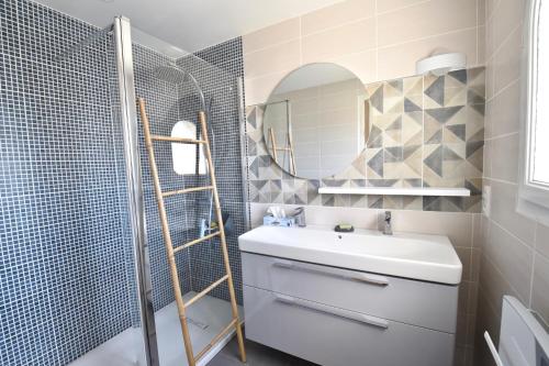 La salle de bains est pourvue d'un lavabo, d'un miroir et d'une douche. dans l'établissement Villa 7 chambres avec grande piscine non chauffée à 600 m de la plage, à Royan