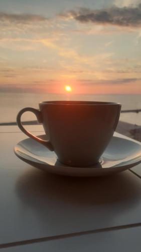 a coffee cup on a plate with the sunset in the background at Maritimo Luxury ApartHotel in Constanţa