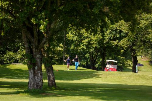two people walking in a park with a golf cart at Waldsee Golf-Resort in Bad Waldsee