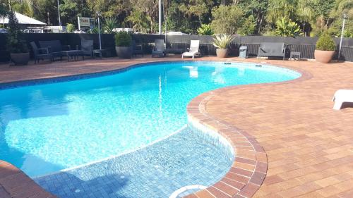 einen Pool mit blauem Wasser in einem Resort in der Unterkunft The Park Hotel Motel, Suffolk Park in Byron Bay