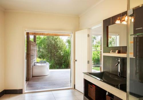 a bathroom with a bath tub and a door to a yard at The Waiheke Lodge in Onetangi