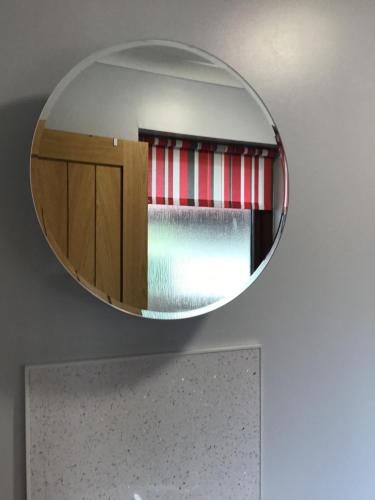 a mirror hanging on a wall with a bed at Riverside Retreat in Caol