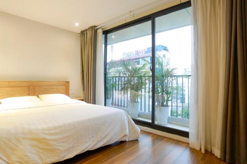 ein Schlafzimmer mit einem Bett und einem großen Fenster in der Unterkunft Alaya 1 Apartment in Hanoi