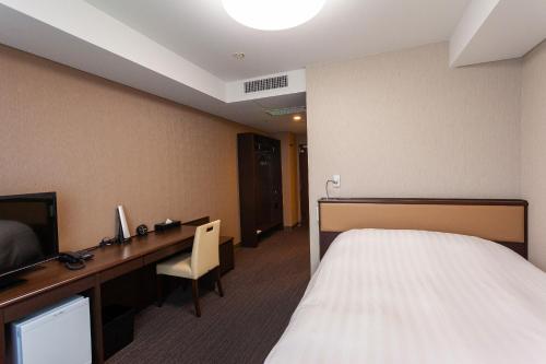 ein Hotelzimmer mit einem Bett und einem Schreibtisch in der Unterkunft Silk Hotel in Iida