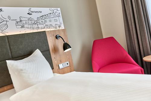 a room with a bed and a red chair at Hotel Pfeffermühle in Siegen