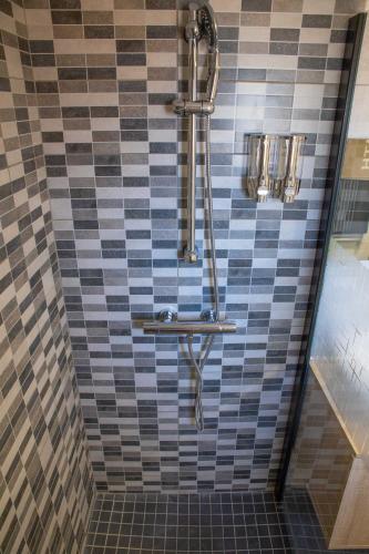 La salle de bains est pourvue d'une douche et d'un mur carrelé. dans l'établissement Le chalet aux Etoiles Spa & Sauna, à Pézenas