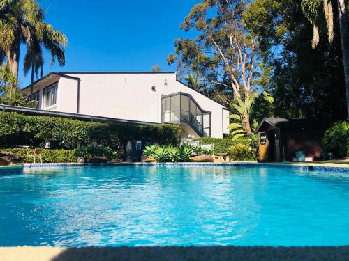 a large swimming pool in front of a house at Checkers Resort in Terrey Hills