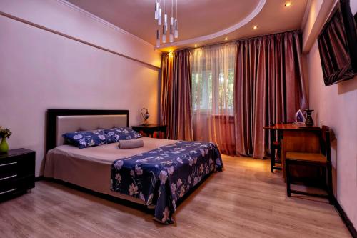 a bedroom with a bed and a desk and a window at 435 Апартаменты в центре для командированных и туристов in Almaty
