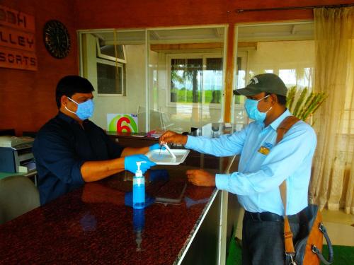 two men wearing face masks standing at a counter at Rainforest Resort and Spa, Igatpuri -Nature's Luxury Awaits in Igatpuri