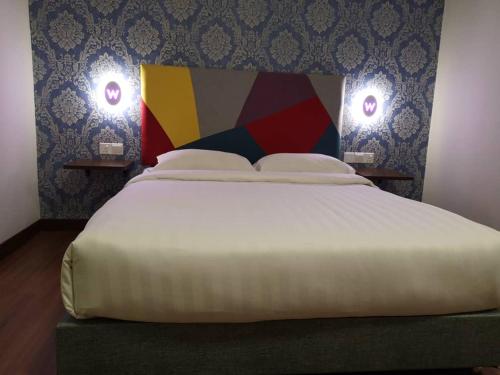 a bedroom with a large bed with two lights on the wall at W Hotel Cemerlang in Kota Bharu
