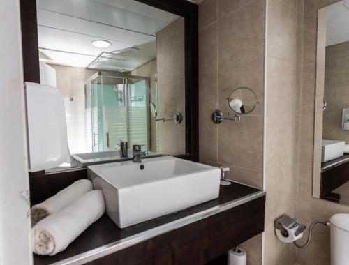 G hotel في إيلات: حمام مع حوض أبيض كبير ومرآة