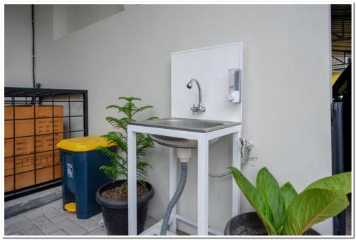 a sink in the corner of a room with plants at RedDoorz near Sleman City Hall 2 in Yogyakarta